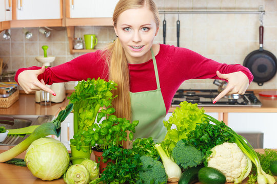 Woman in kitchen having many green vegetables