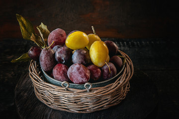Ripe and juicy yellow and blue plums in a wicker basket in a rustic style. Happy Thanksgiving.