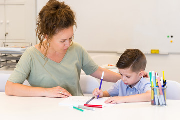 teacher woman drawing with child boy in a classroom