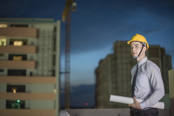 Smiling young architect or engineering builder in hard hat with tablet over group of builders at...