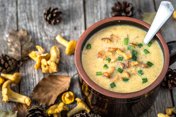 Cream soup with mushrooms and fresh chanterelles mushroom on wooden rustic background