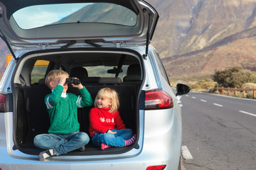 little boy and girl travel by car in mountains