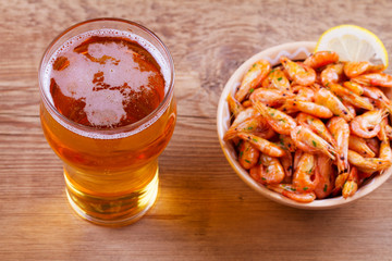 Beer and shrimps in bowl on wooden background. Glass of beer and prawns. Ale. View from above, top studio shot