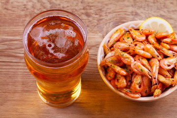 Beer and shrimps in bowl on wooden background. Glass of beer and prawns. Ale. View from above, top studio shot