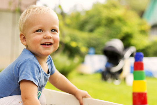 CLose-up Portrait Of Cute Smiling Baby Boy On The Blurred Nature Background. Copy Space