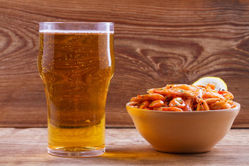 Beer and shrimps in bowl on wooden background. Glass of beer and prawns. Ale