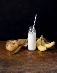 Bottle milk with straw, sandwich with peanut butter and banana