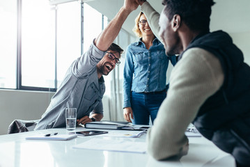 Two colleagues giving high five during meeting