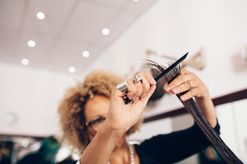 Female hair stylist cutting woman 's hair at salon - obrazy, fototapety, plakaty