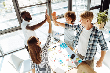 Cheerful young colleagues giving high five