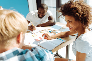 Obraz premium Psitive female afro american student studying with her groupmates