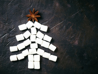 Christmas tree made from marshmallow and star anise on black concrete background