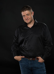 Young confident man portrait of a confident businessman showing by hands on a black background. Ideal for banners, registration forms, presentation, landings, presenting concept.