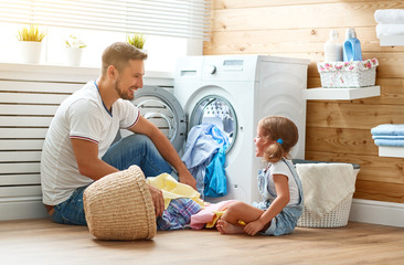 Happy family man father householder and child   in laundry with washing machine - obrazy, fototapety, plakaty