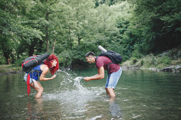 Fototapeta premium Happy young hikers couple enjoying in adventure. They camping and having fun while walking through the wild mountain river.