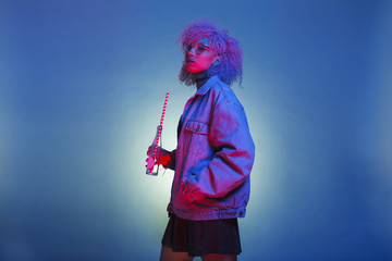vintage black woman with trendy clothes drinking a soda on neon lights