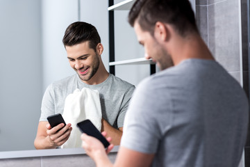 man using smartphone in bathroom
