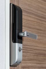 modern electronic door lock with handle on wooden door, security system for condominium or hotel