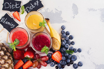 Assortment of bright fruit and berry smoothies on white table. Summer refreshing drinks. Detox or diet concept