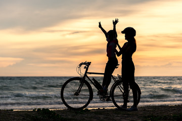 Obraz na płótnie Canvas Biker family silhouette at the beach at sunset..