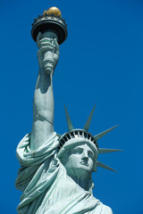 Fototapeta na wymiar Statue of Liberty detail with golden torch, blue sky in New York