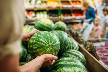woman picking watermelon in grocery shop