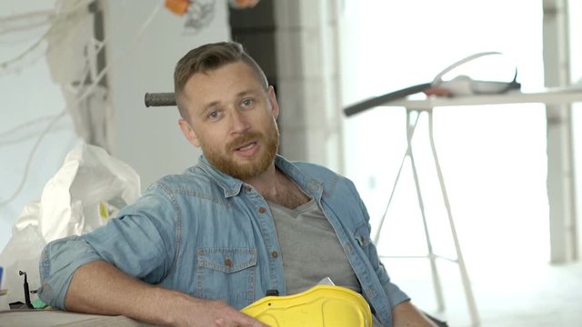 Handsome man holding helmet and telling something to the camera, steadycam shot
