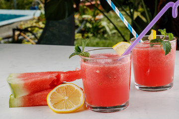 Watermelon smothie and slices with lemon on light gray background