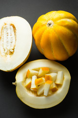 Fresh organic melons sliced on black background.