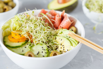 salmon poke with rice, avocado and sprouts.