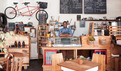 Young African entrepreneur standing behind the counter of his cafe