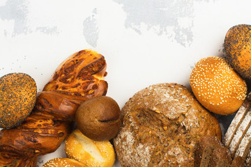 Assortment of fresh baked bread and buns on kitchen table. Space for text. Top view