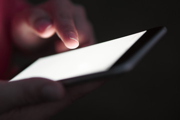 Close-up. The girl points to the phone screen in the park. Dark background. Lanterns of streets. Bright phone screen