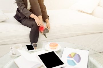 Young asian Businesswoman sitting on sofa massaging her foot .Hurting feet while wearing high heels all day.Office syndome.