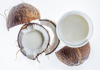 cracked coconut with glass of coconut milk, isolated on white