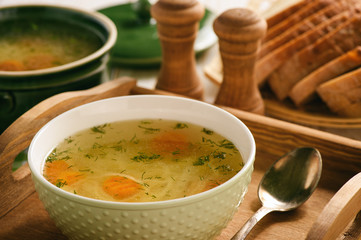 Chicken soup in bowl on wooden tray.