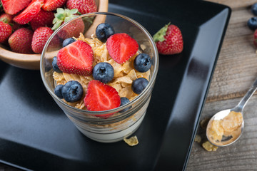 Fresh yogurt with muesli and berries on a wooden table, healthy breakfast