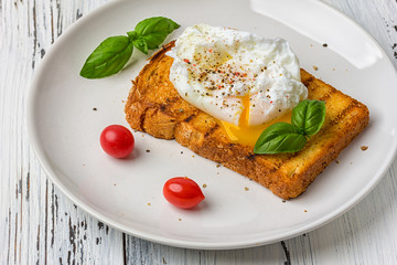 Poached egg on a piece of bread on the wooden table