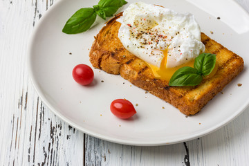 Poached egg on a piece of bread on the wooden table