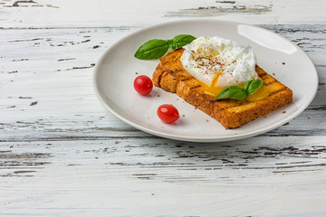 Poached egg on a piece of bread on the wooden table