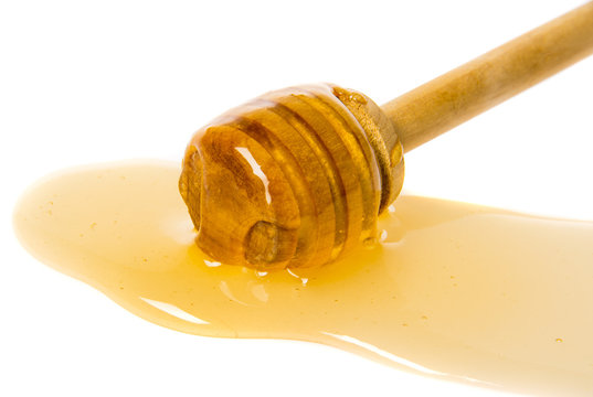 Honey dripping from honey dipper isolated on a white background