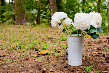 A bouquet of white flowers in a vase in the forest. Wedding decorations.