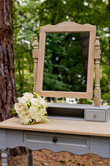 A wedding bouquet in the forest on a table with a mirror. Wedding decorations.