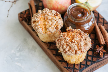 Apple cinnamon crumble muffins on a wooden board. White stone background. Close up and copy space.