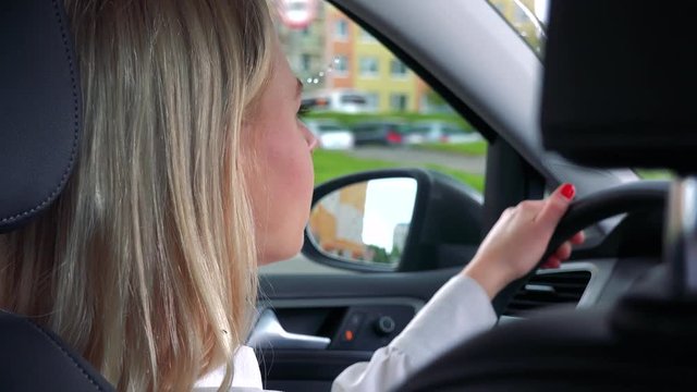 Young attractive blond woman drives a car in rainy day - road in the city - closeup