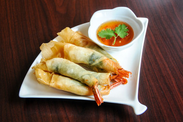 Shrimp Rolls, Whole shrimp rolled with basil leaves in a crispy rice wrapper, fried & served with our tangy homemade sweet & sour sauce.