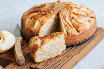 Easy apple tea cake on a wooden board. White stone background. Homemade baking.