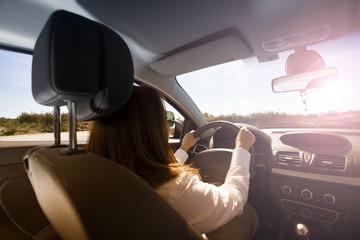 Fototapeta premium Young beautiful girl driving a car. Rear view.