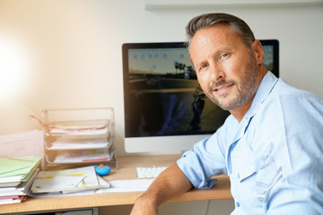 Cheerful mature man sitting in home-office