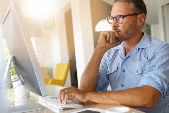 Mature man working from home on desktop computer